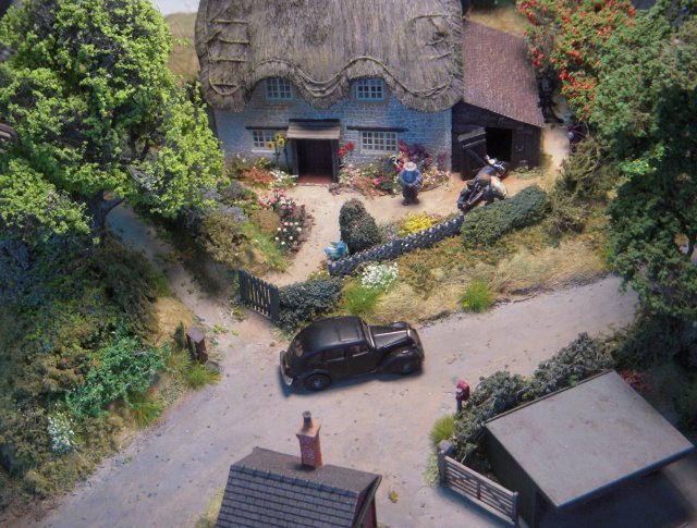 Hobbs Row Halt was a classic English country micro-layout, complete with thatched cottage and "chocolate box" garden.  It started out as a simple circular piece of track on an MDF wobble board, obtained from a local charity shop, used for running in new locomotives before some surplus buildings from Bob's Tansey Bank layout were added to check on coach clearances.  The cottage was from the Bachmann Pendon Little Chapel Cottage resin model while the trees were from the Realistic Modelling Materials range of ready to plant foliage.  Hobbs Row Halt, complete with tram engine "Lawrence" below, featured in the August 2013 edition of Hornby Magazine.