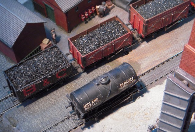 The green and white palette of the gas works manager's elevated house and garden made a pleasing contrast to the red and grey tones of the gas works itself and rail traffic included both open wagons to deliver the coal to the retorts and tank wagons, such as the Midland Distillers vehicle seen below next to the grey diagonally piped cooling stack, to take away the by products of the gas production process.  