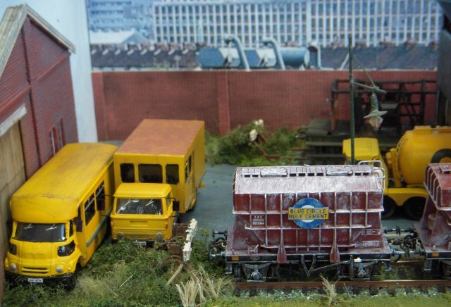 Pallet Lane was an imaginary BR station set around 1977, inspired by the Severn Beach to Bristol branch and built on baseboards recovered from two forklift pallets. The line would have continued beyond Pallet Lane in pre Beeching times but nearby factories and oil and cement terminals ( pictured above) justified its continued survival and that of a DMU passenger service. Already known for his modelling demonstrations at St Margaret's Hall, Rob Owst had made a particularly fine job of the "distressed" scenery at Pallet Lane, especially the corrugated iron platform shelter which was weathered with real rust! The cement terminal was based on that at nearby Lawrence Hill and the fuel oil siding on the 8'6" x 1'6" layout was similar to ones around Shirehampton. However, the location of Pallet Lane can vary with the weathered BR blue stock used and a welcome addition for this show was the town area, including the Land Rover enthusiast's back yard behind the green door on the street pictured below.